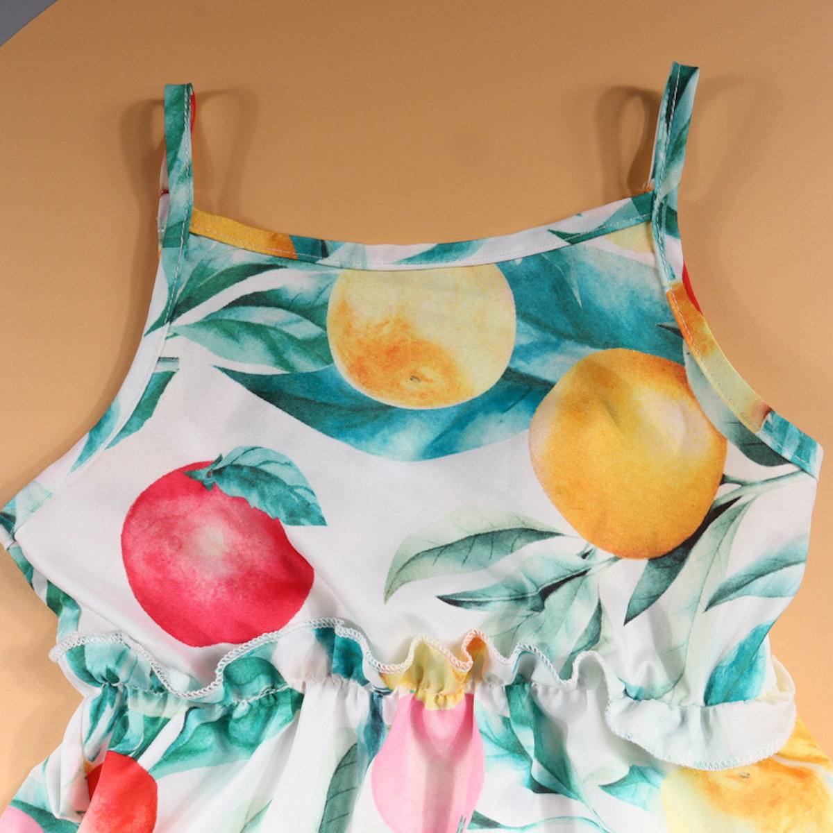 Children's dress with fruit and leaf pattern on a beige background