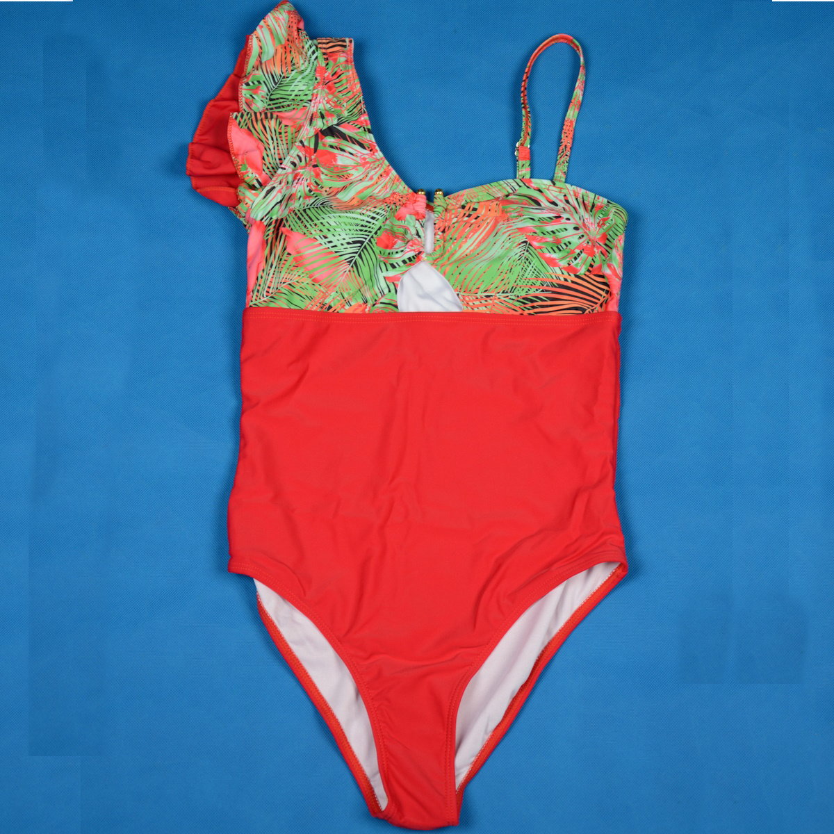 Red swimsuit with green floral top on a blue background