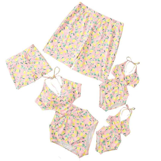 Set of pink and yellow floral swimwear with matching accessories on a white background