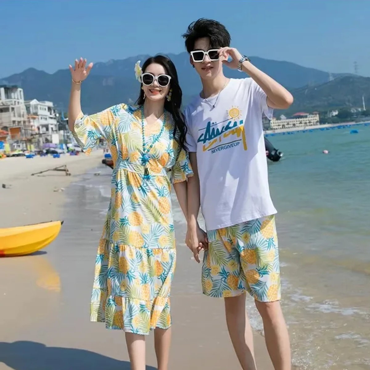 Two people in matching pineapple-patterned outfits on a beach with mountains in the background  Pineapple Family Matching Outfits - ChildAngle