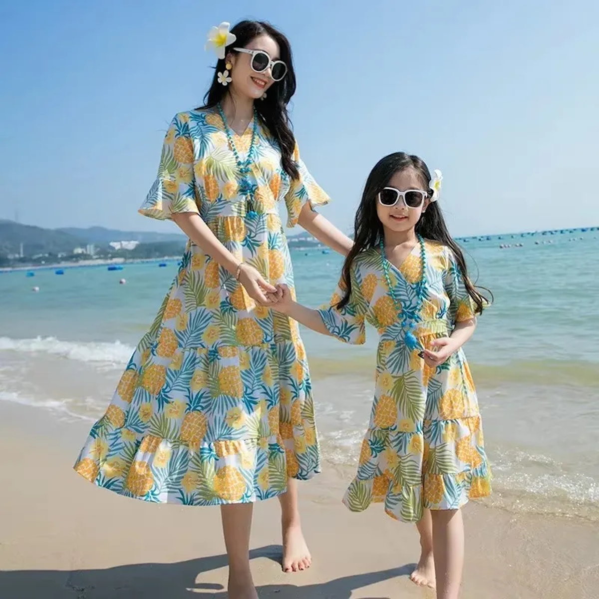 Two women in matching pineapple-patterned dresses standing on a beach  Pineapple Family Matching Outfits - ChildAngle