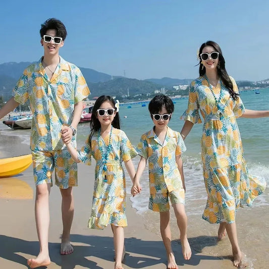 Family of four in matching beach outfits standing on a sandy beach with ocean and mountains in the background Pineapple Family Matching Outfits - ChildAngle