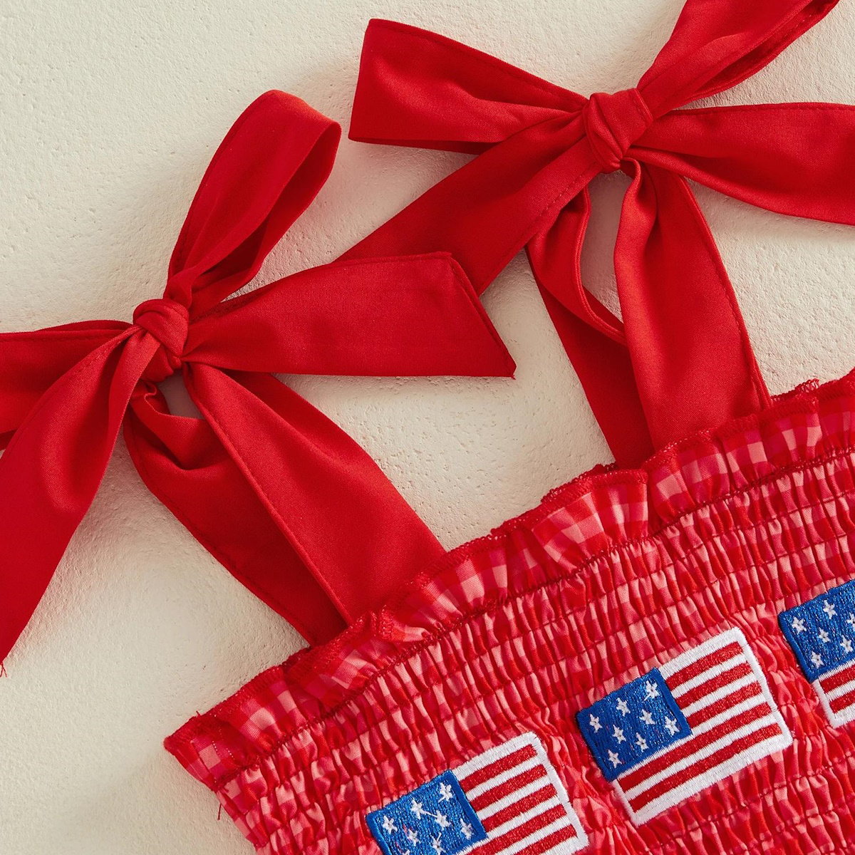 Child in a red checkered outfit with American flags - ChildAngle 4th of July Baby Romper