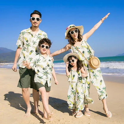 Family of four posing on a beach with ocean and sky in the background