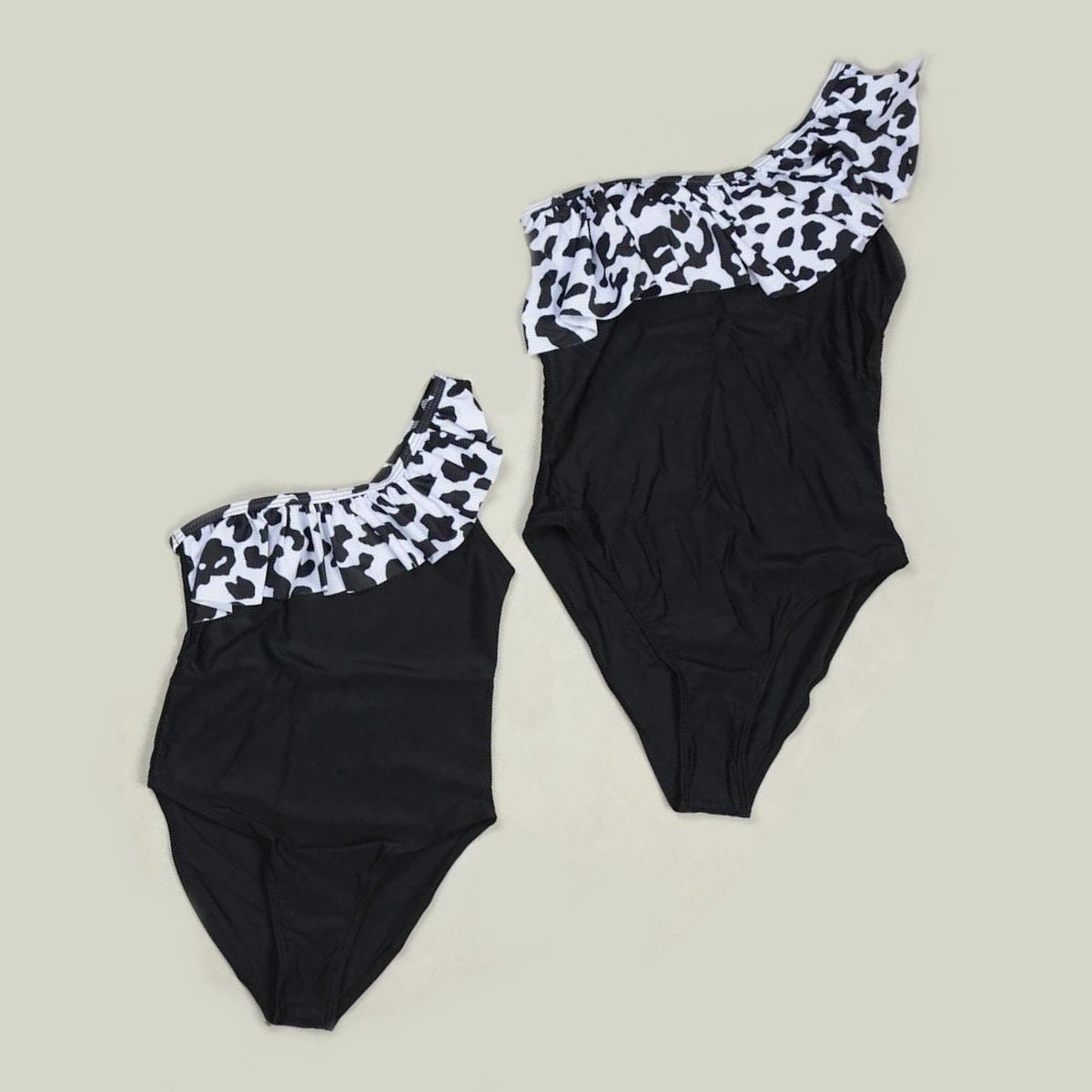 Black swimsuit with white and black patterned top on a beige background