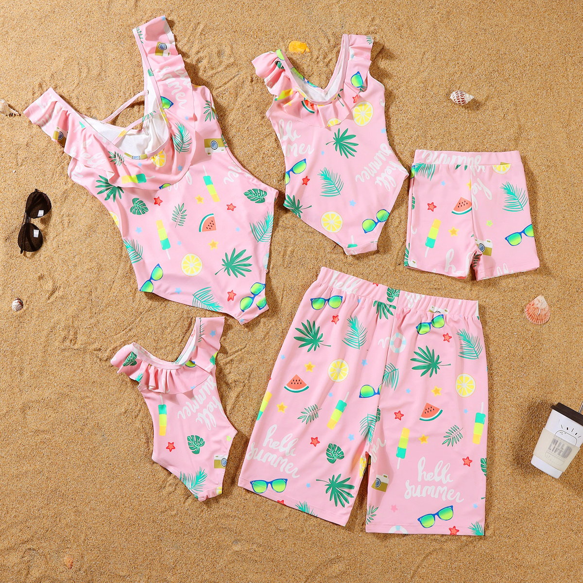 Pink children's swimwear set with tropical patterns on a sandy background