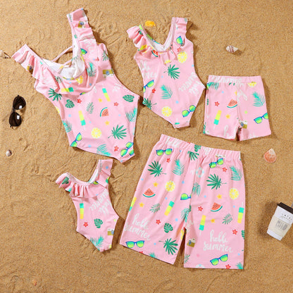 Pink children's swimwear set with tropical patterns on a sandy background