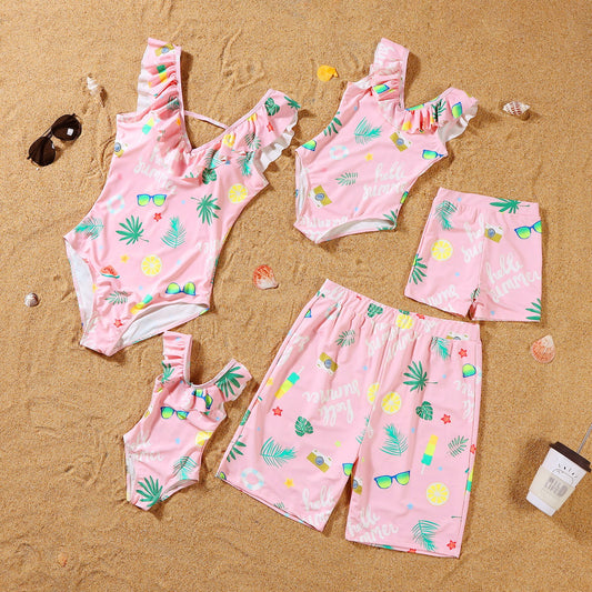 Pink children's swimwear set with tropical patterns on a sandy background