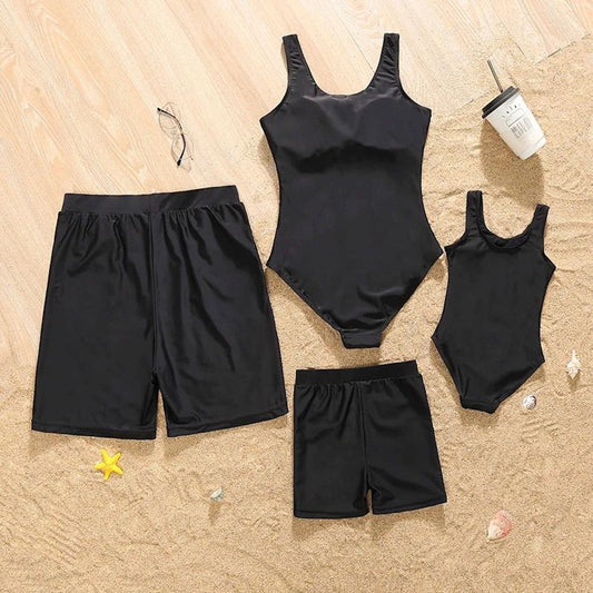 Black swimsuits and shorts on a sandy surface with beach accessories.
