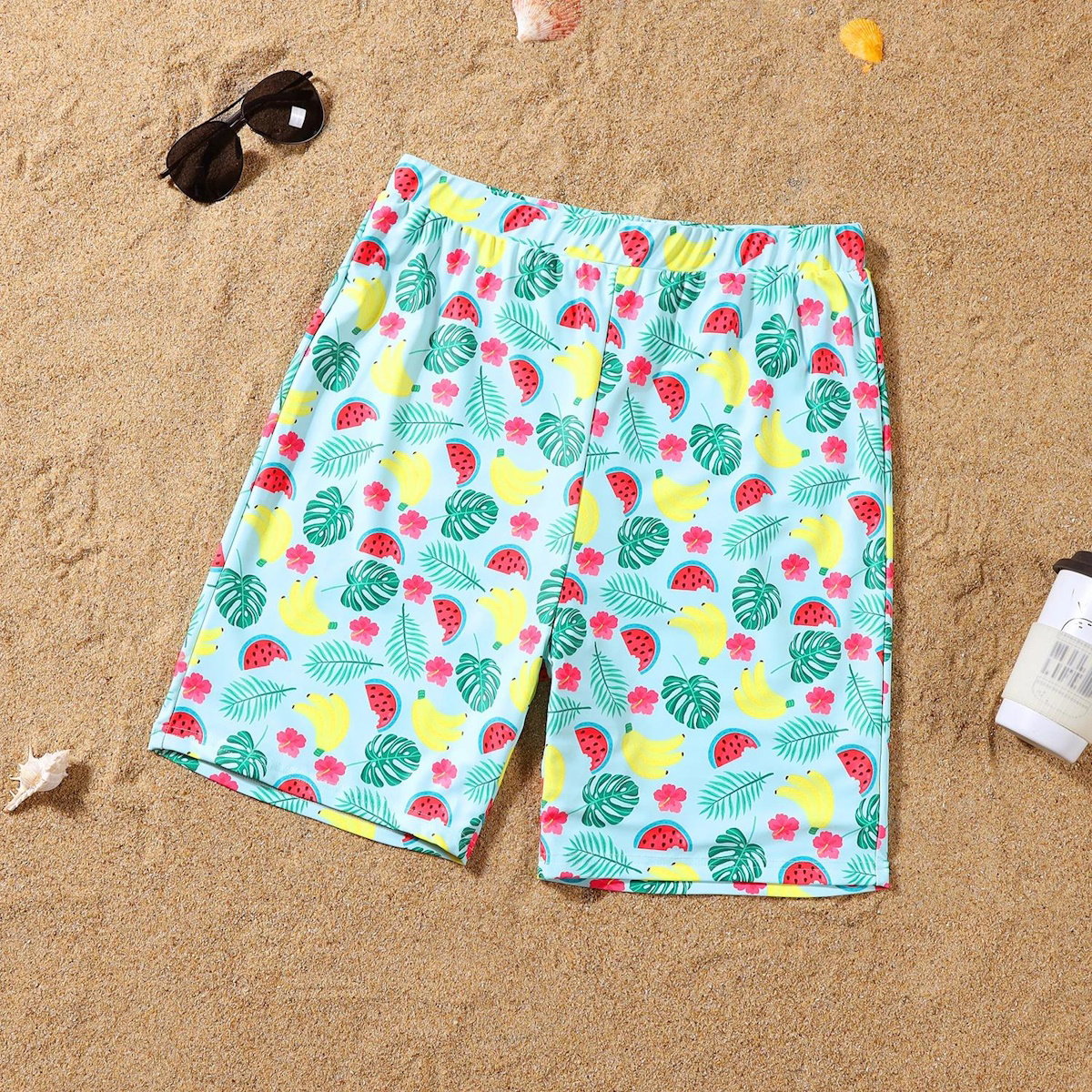 Colorful tropical fruit patterned shorts on a sandy background