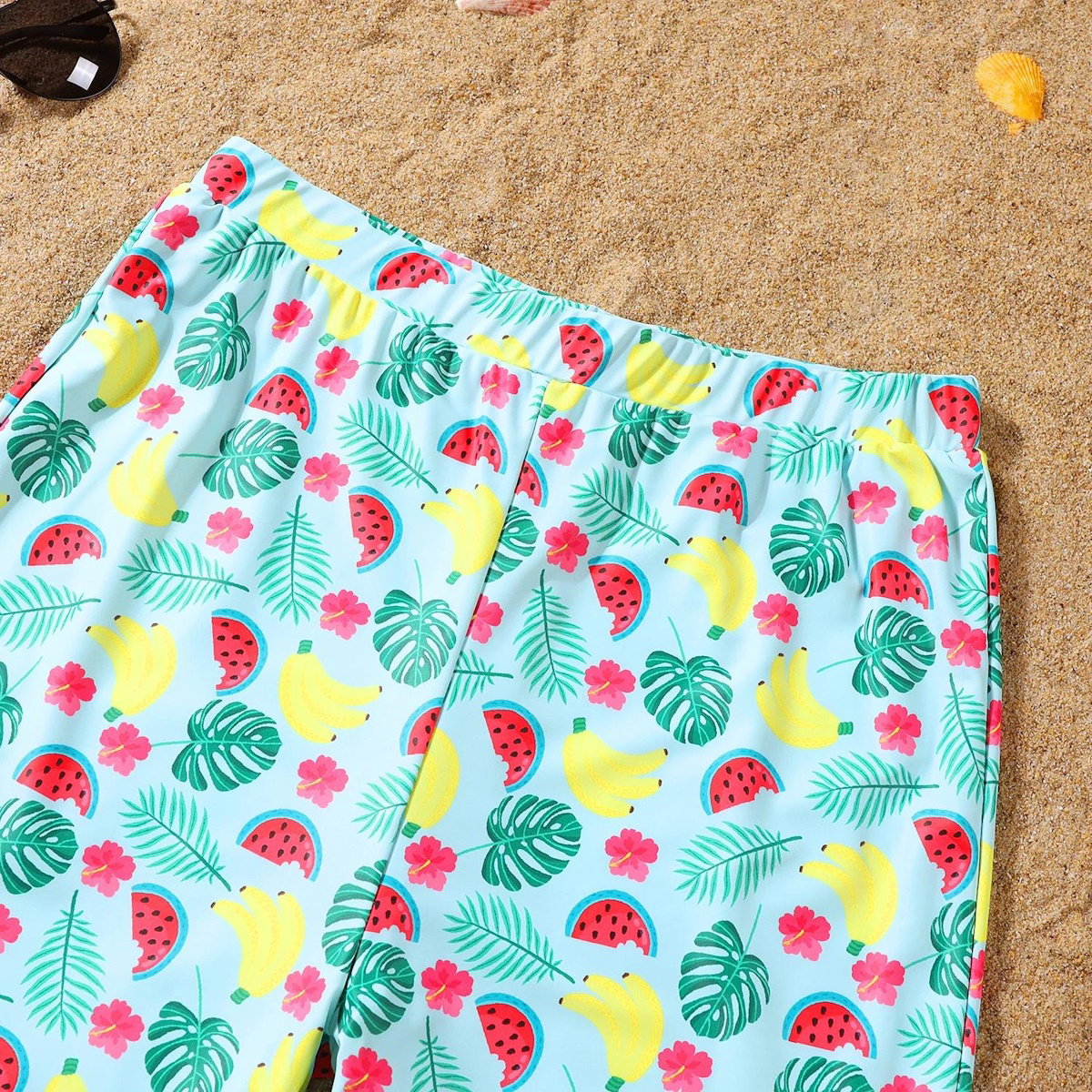 Colorful beach towel with tropical pattern on sand