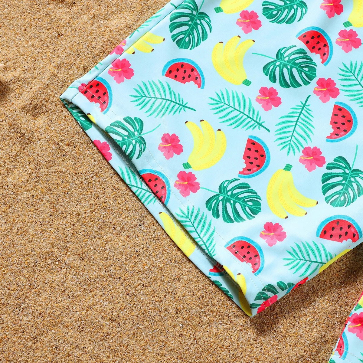 Colorful beach towel with tropical pattern on sand