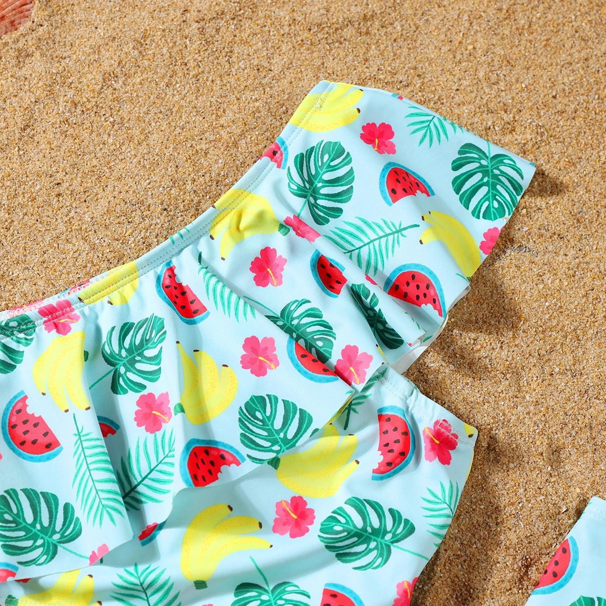 Colorful swimsuit with tropical pattern on a sandy background