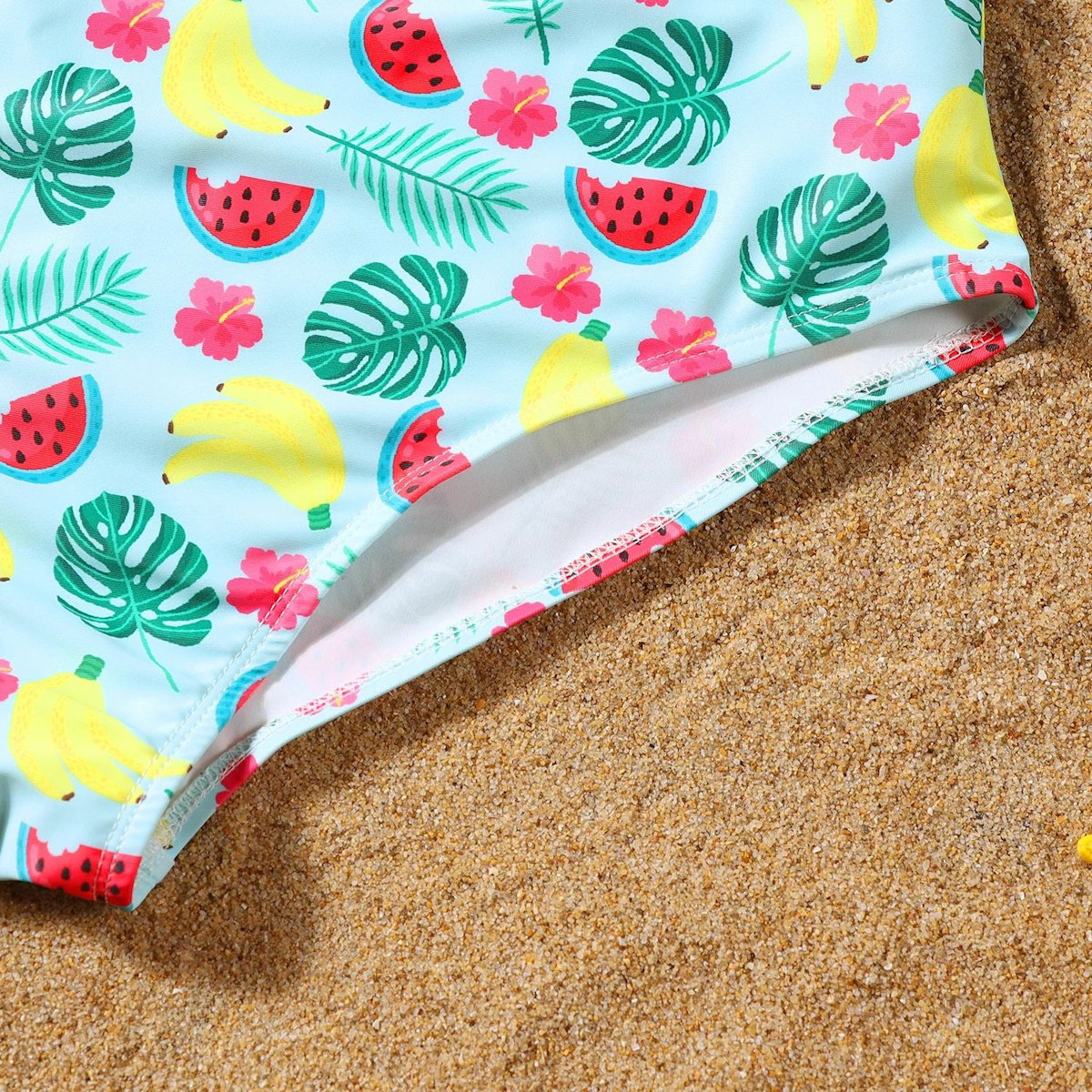 Colorful beach towel with tropical patterns on sand
