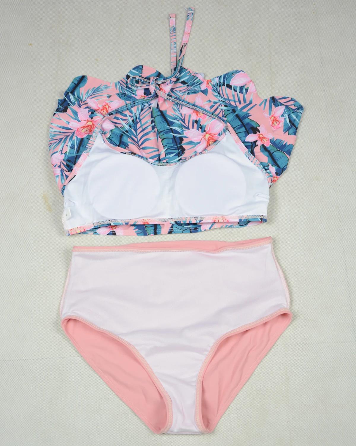 Two-piece swimsuit with floral top and pink bottom on a light gray background