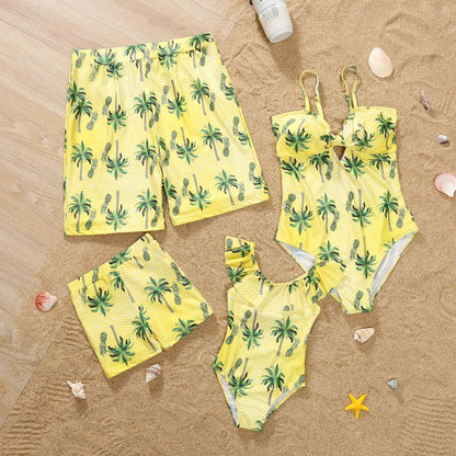 Yellow swimwear set with palm tree pattern on a sandy background