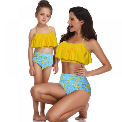 Woman and child wearing matching yellow tops and blue banana-patterned bottom - ChildAngle